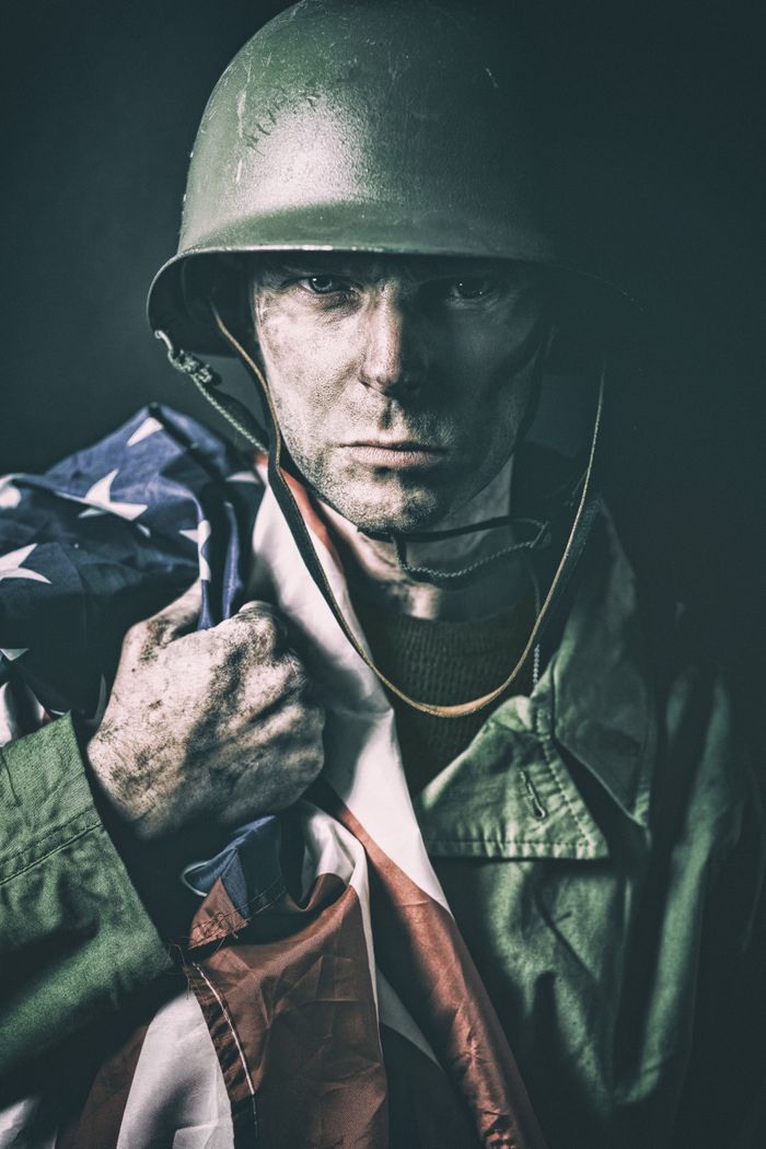 Close-up portrait of a soldier in uniform, holding a flag, exuding strength and determination.