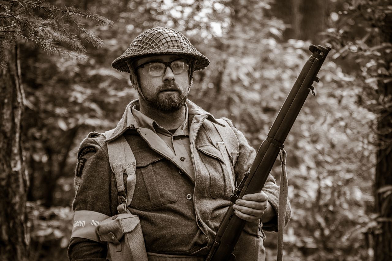 A sepia-toned image of a historical reenactor soldier with rifle in an English forest.