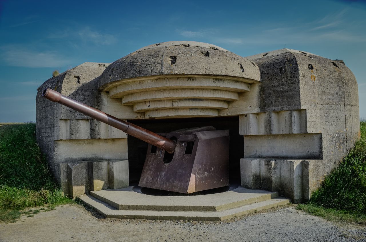 Photograph of a World War II bunker with a cannon in Normandy, France.